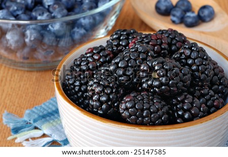 Fresh blackberries in ceramic dish with blueberries in the background.  Macro with shallow dof.  Selective focus on front blackberries.