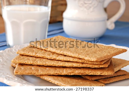 Graham crackers on vintage plate with pitcher and glass of milk in background.  Close-up with shallow dof.