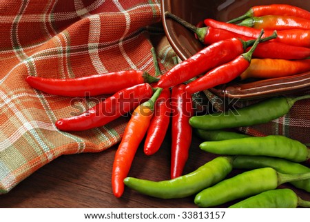 Chili peppers spilling from small bowl with colorful kitchen towel as background.  Macro with shallow dof.