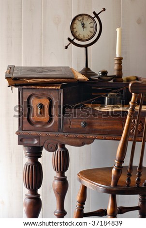 Still life of antique secretary desk from the early 1900s with vintage accessories.  Soft natural side lighting shows details including nicks and scratches from wear.