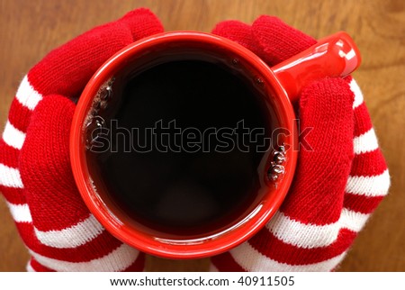 Gloved hands holding mug filled with hot beverage.  Macro with shallow dof.  Copy space inside mug.