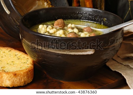 Traditional Italian wedding soup in rustic stoneware bowl with toasted garlic bread.  Close-up with shallow dof.