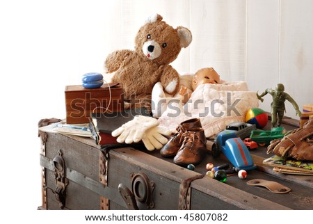 Vintage background with collection of antique childhood treasures on rustic old steamer trunk.  Fades into white background for copy space.
