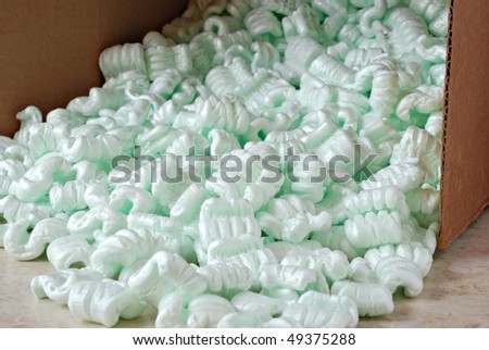Packing peanuts spilling from open cardboard box.  Close-up with shallow dof.  Focus on front edge of box.