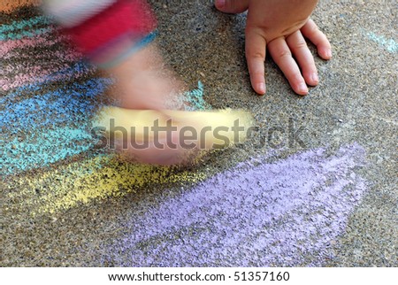 Artistic image of young child scribbling aggressively with colorful sidewalk chalk.  Motion blur created in camera for effect.