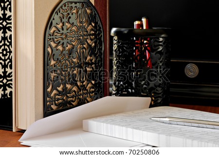 Classic letter writing still life with decorative bookends and pen holder in background.  Closeup with shallow dof.