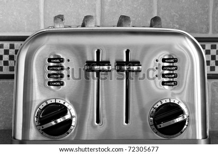Black and white image of classic retro styled toaster with sliced bread.  Decorative tiled backsplash in background.