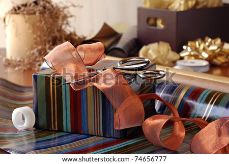 Gift wrapping still life with partially wrapped gift, ribbon and supplies.  Closeup with shallow dof.