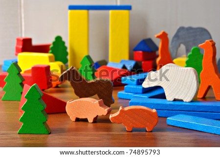 Tiny colorful wooden toy shapes and building blocks on hardwood floor.  Macro with extremely shallow dof.  Selective focus on toys in foreground.