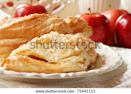 Delicious apple turnovers on decorative plate with fresh gala apples in background.  Closeup with shallow dof.