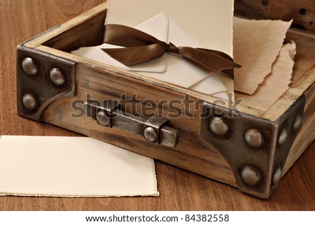 Rustic wooden desk drawer with parchment stationery and envelopes tied with satin ribbon. Blank note card included in composition for copy space.  Macro with shallow dof.