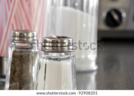 Nostalgic still life of retro diner counter with salt and pepper shakers, sugar, and straw dispensers.  Macro with shallow dof.  Selective focus on salt.