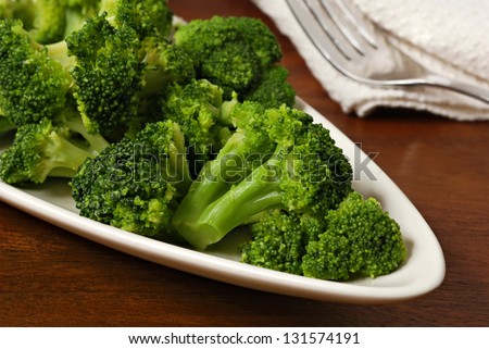 Freshly steamed broccoli on plate with fork and napkin in background. Macro with shallow dof.