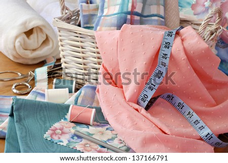 Still life image of sewing basket with pretty pastel fabrics and supplies for home decor or quilting project.  Roll of cotton batting and pinking shears in background.  Closeup with shallow dof.