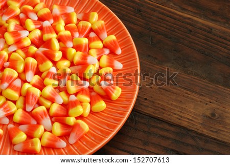 Candy corn in orange dish on rustic wood background with copy space.
