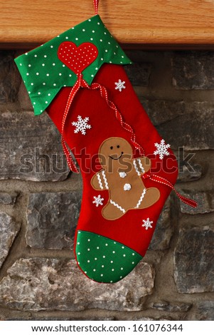 Christmas stocking (with smiling gingerbread man holding a heart shaped balloon) hanging from mantel of stone fireplace.  Stocking is an original design created and handcrafted by me.