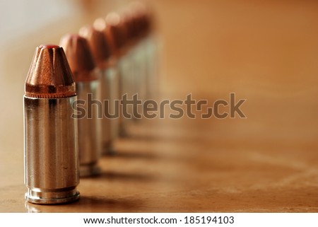 9mm polymer tipped bullets (used for concealed carry guns) on wood background.  Macro with shallow dof and copy space.  Selective focus limited to first bullet.