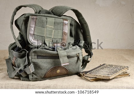 Tarpaulin backpack and old books on the canvas