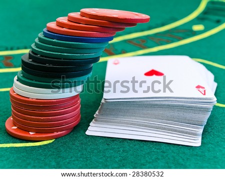 stack of chips next to a deck of playing cards in a casino on the green table