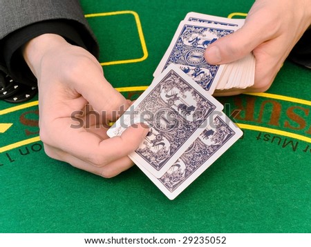 the hands of men sit playing cards at a table in a casino