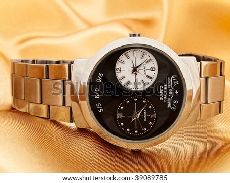 fashioned man watch at golden fabric