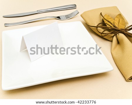 decorated table serving with golden bay leaves in serviette and cord near plate, knife and fork at beige