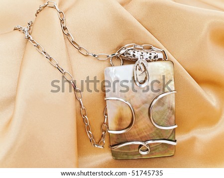fashion necklace with metal decoration over golden textile background