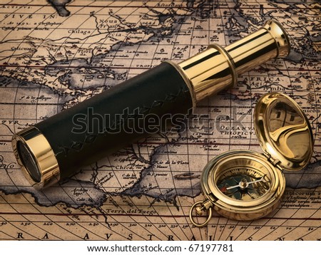 traveling theme: vintage telescope and compass at antique map