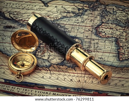 traveling theme: vintage telescope and compass at antique (17 century) map