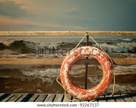 Storm at the sea, pier with life buoy