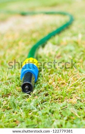 Gardening water pipe lying and dripping a drops of water to dry ground druing hot summer