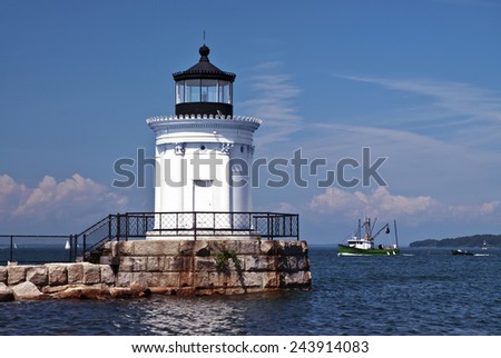 Portland Breakwater lighthouse, also known as Bug light, guides a fishing trawler into the harbor.