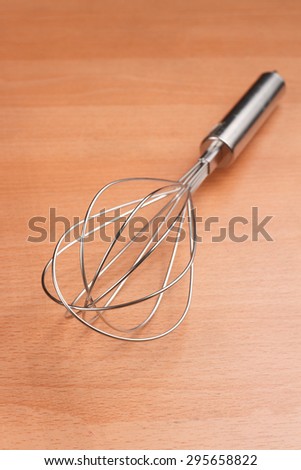 closeup whisk or egg beater on wooden table , selective focus