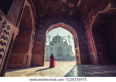 Beautiful woman in traditional dress costume,Asian woman wearing typical saree/sari dress identity culture of India. Taj Mahal Scenic The morning view of Taj Mahal monument  at Agra, India.