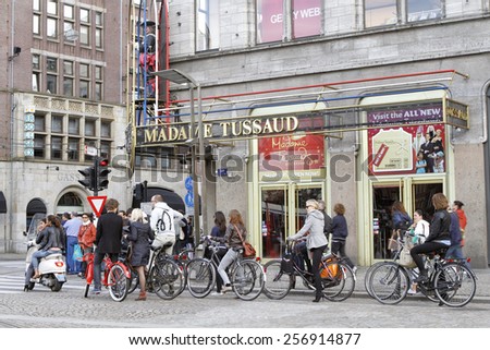 AMSTERDAM, NETHERLANDS, JULY 12, 2012: Bicycle riders stopping for red traffic light infront of Madame Tussaud\'s. Amsterdam is one of the most bicycle-friendly large cities in the world.