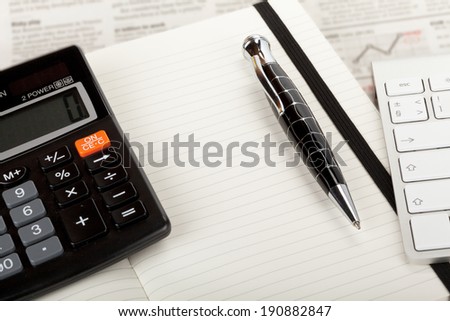 Business newspaper overview with open book, keyboard and calculator.