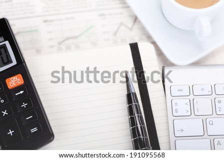 Business photo: coffee with open book, pen, calculator, newspaper (stock index overview) and keyboard