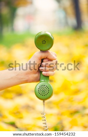 hand holding vintage phone receiver in autumn park