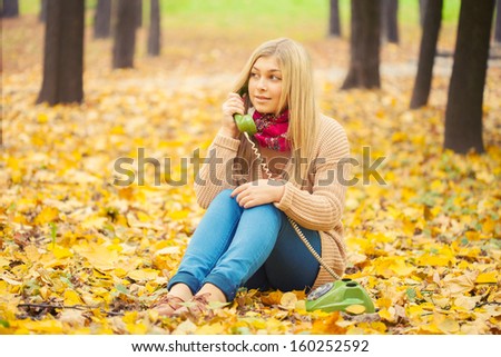 young woman talking on vintage phone in autumn park