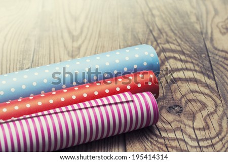 Rolls of colored wrapping paper on wooden background