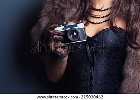 woman wearing corset and fur and holding vintage camera