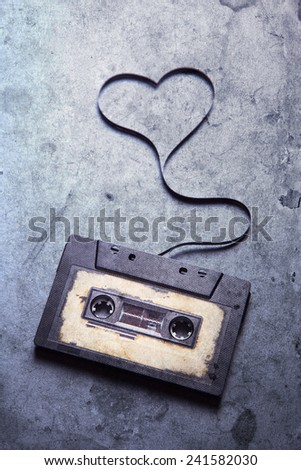 audio cassette with magnetic tape in shape of heart on grunge background