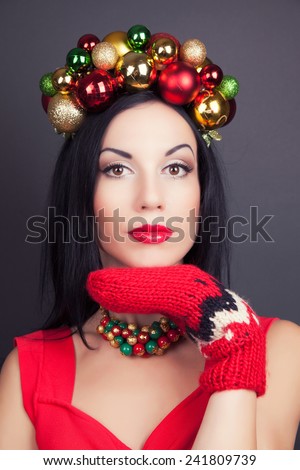 beautiful woman wearing a wreath made from Christmas decorations and red mittens