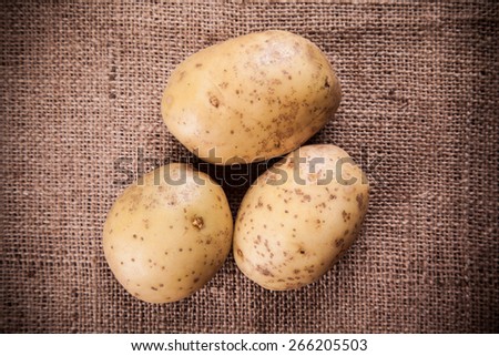 Fresh Potato with Vintage Burlap Bag on Wood Table Background