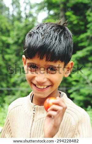 SRINAGAR, INDIA. JUNE 24, 2012 : The Indian young boy show products to travellers at tomato farm in Srinagar, North of India
