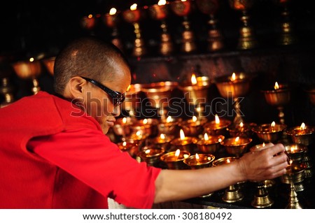 INDIA, LEH, JUNE18, 2012 : Tibetan nun lights prayer lamps at old temple, Tibetan Buddhism\'s most holy temple. Leh, North of India