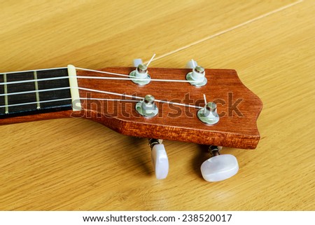 An ukulele on wood background , small guitar