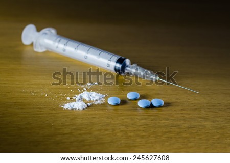 Drug syringe and cooked heroin on wood table