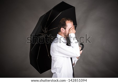 business man with an umbrella in hand covers his face