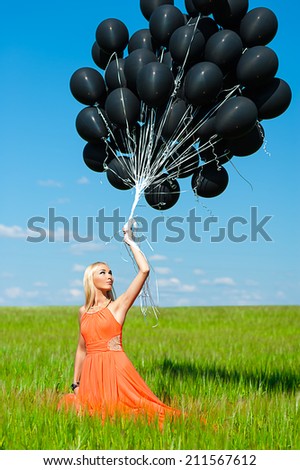 beautiful woman looking up at the black balloons
